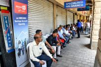 Customers wait outside a Yes Bank branch in Mumbai after a run on deposits