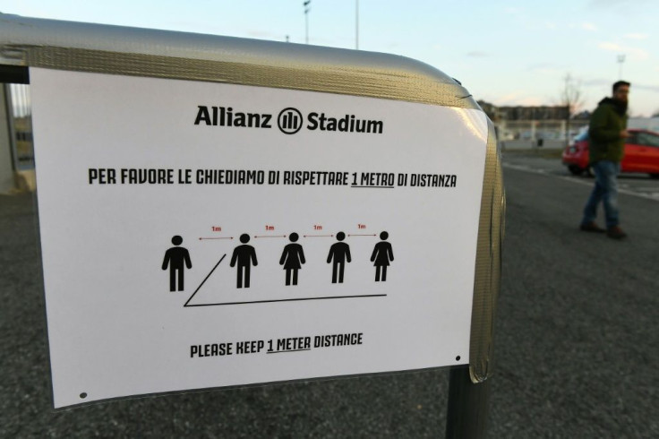 A man passes a sign explaining that a distance of one metre is required between people arriving at the Juventus stadium