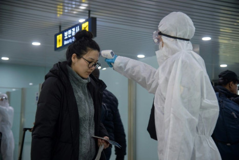 A woman has her temperature taken as foreign diplomats and embassy staff prepare to board a flight to Vladivostok at Pyongyang International Airport
