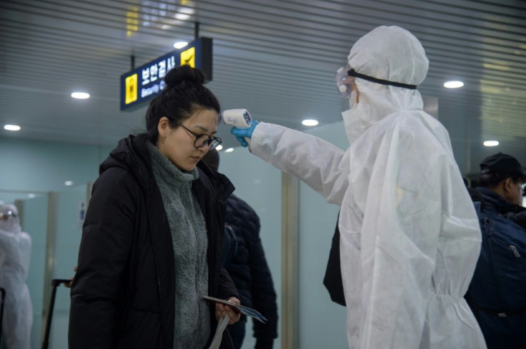 A woman has her temperature taken as foreign diplomats and embassy staff prepare to board a flight to Vladivostok at Pyongyang International Airport