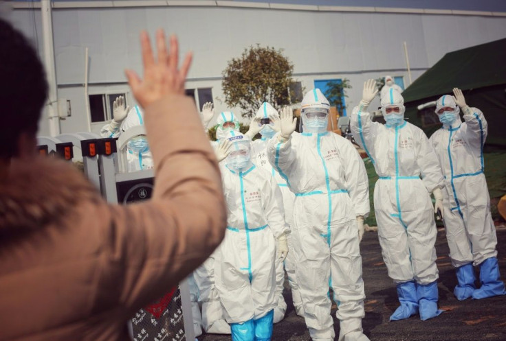Medical staff members wave to a recovered patient at a makeshift hospital for the COVID-19 coronavirus patients in Wuhan