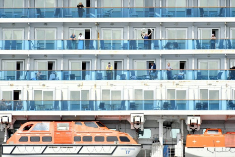 A woman waves as others look out from aboard the Grand Princess cruise ship, operated by Princess Cruises, as it maintains a holding pattern about 25 miles off the coast of San Francisco, California