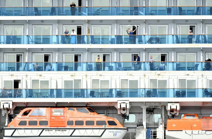 A woman waves as others look out from aboard the Grand Princess cruise ship, operated by Princess Cruises, as it maintains a holding pattern about 25 miles off the coast of San Francisco, California