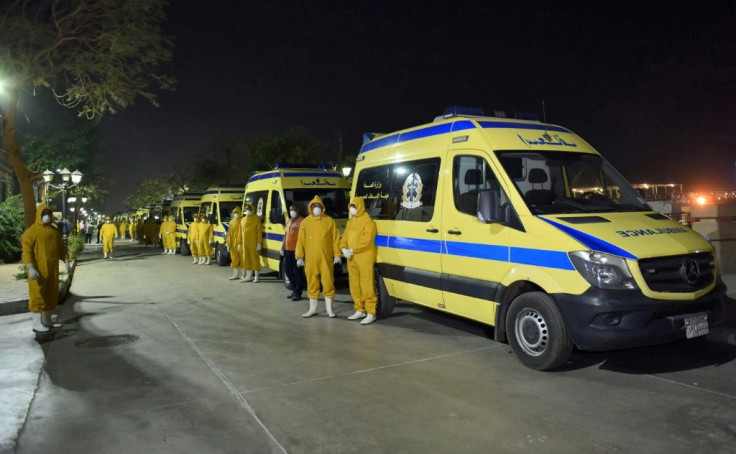 Egyptian health ministry emergency responders stand next to ambulances ready on the scene to transport suspected COVID-19 coronavirus disease cases that were detected on a Nile cruise ship