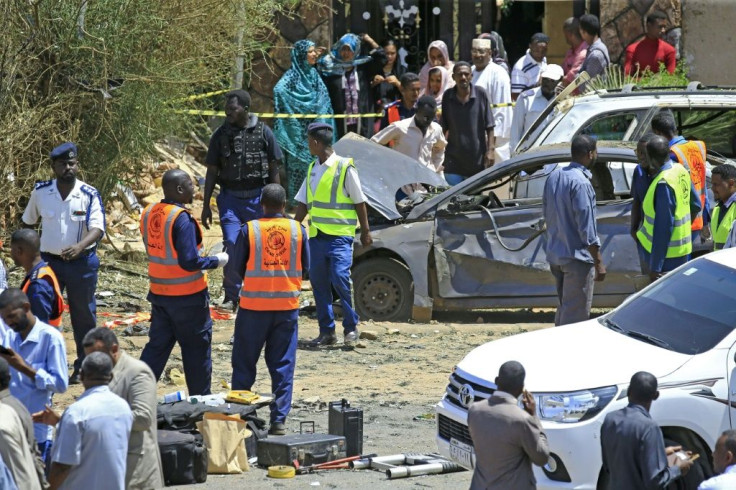 Sudanese rescue teams and security forces circle damaged vehicles at the site of a bomb attack targeting the convoy of Prime Minister Abdalla Hamdok, who survived the attack unharmed