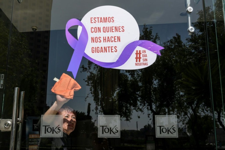 A woman cleans the glass door of a Mexico City restaurant with a sign reading 'We stand with those who make us giants' during Monday's 'A Day Without Us' protest