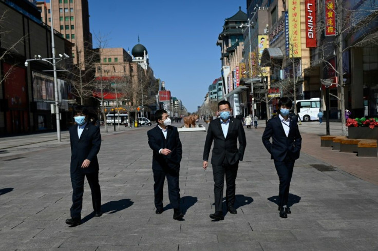 Men wearing face masks walk down a street in Beijing