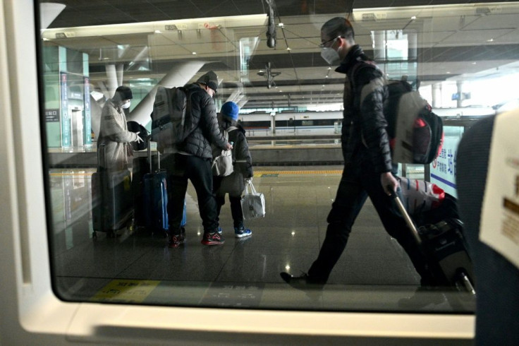 Mask-clad passengers alight from their train at the railway station in Wuhan
