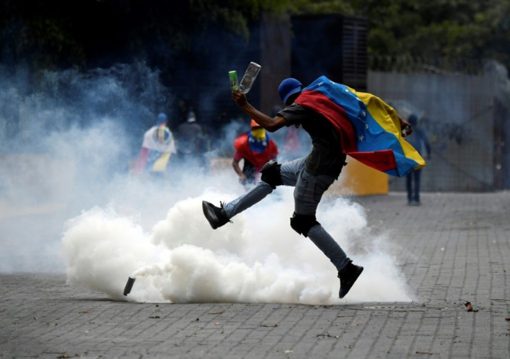 A protester kicks back a tear gas canister fired by security forces on opposition marchers in Caracas