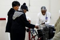People wait to put their ballots in the tabulation machine at Chrysler Elementary School in Detroit