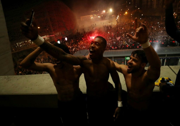 Paris Saint-Germain players Marquinhos, Presnel Kimpembe and Juan Bernat celebrate with supporters gathered outside the ground after beating Borussia Dortmund behind closed doors to reach the Champions League quarter-finals
