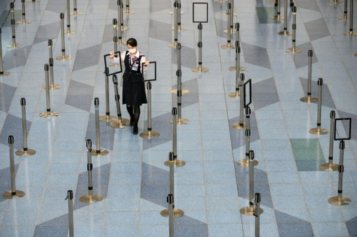 A facemask-clad airline employee works in a near empty the departure hall at Tokyo's Haneda Airport