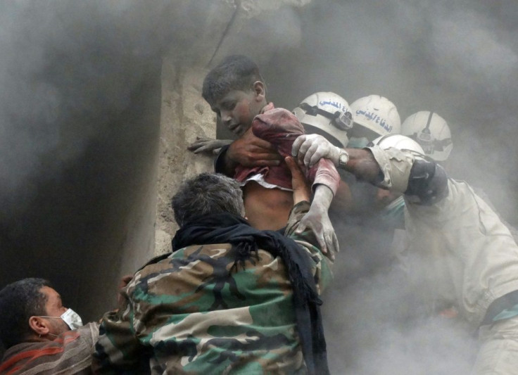 Emergency responders evacuate a Syrian boy from a residential building reportedly hit by a barrel bomb dropped by government forces in Aleppo's Shaar neighbourhood on April 6, 2014