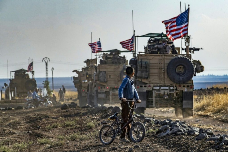 A Syrian boy watches a convoy of US armoured vehicles on patrol near the northeastern town of Qahtaniyah near the border with Turkey on October 31, 2019Â 