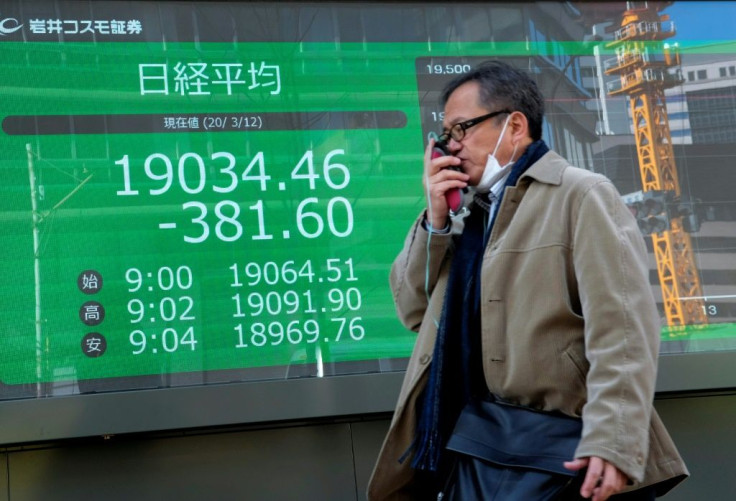 A pedestrian passes in front of a quotation board displaying falling share price numbers at the Tokyo Stock Exchange