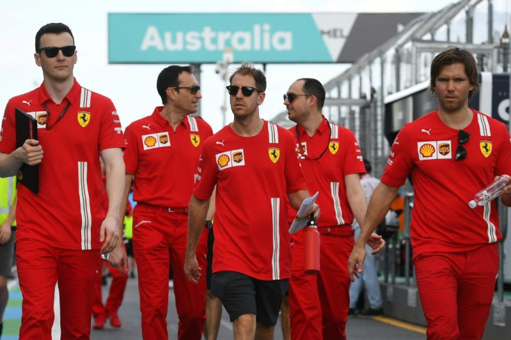 Ferrari's German driver Sebastian Vettel walks down pit lane with team members