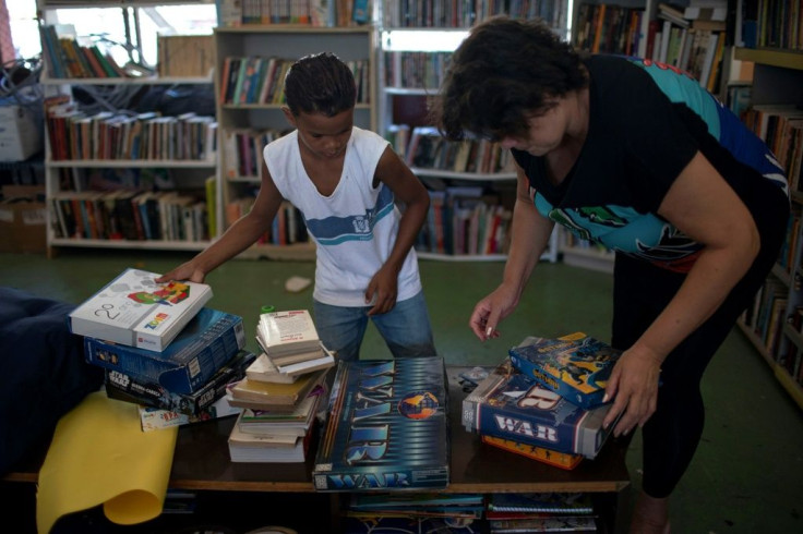 Lua Oliveira's grandmother Fatima Oliveira and a boy organize donated books at the library
