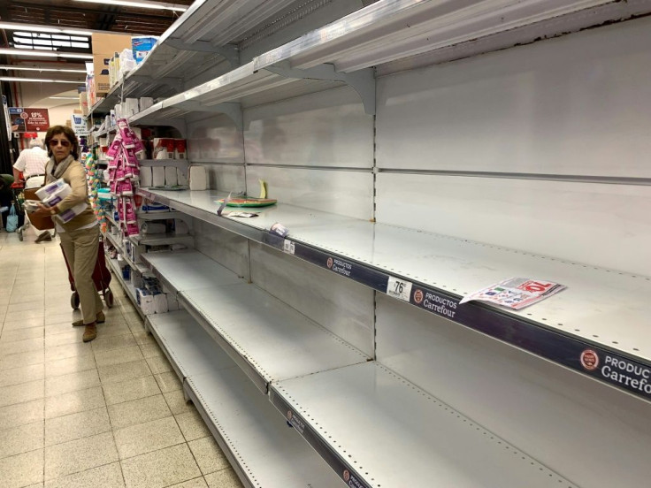 A woman in Argentina walks next to shelves emptied due to fears of the new coronavirus