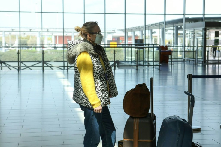 A mask-clad passenger waits at the check-in counters of Larnaca International Airport in the Cypriot coastal city