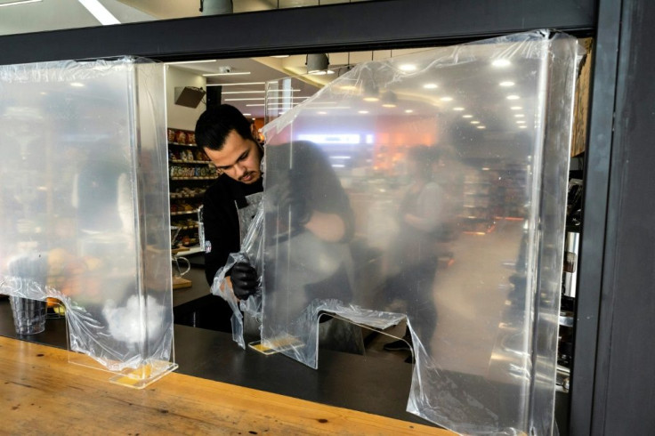 A Cypriot man installs a protective glass barrier at a shop