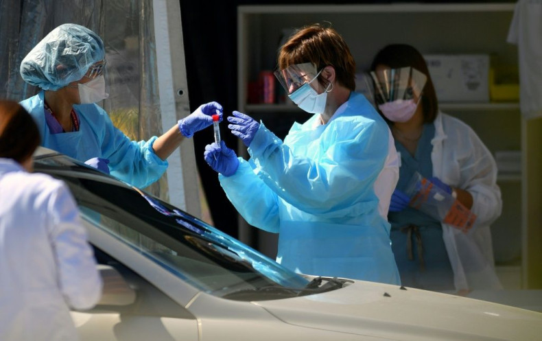 Medical workers at a Kaiser Permanente French Campus test a patient for the novel coronavirus, COVID-19, at a drive-thru testing facility in San Francisco on March 12