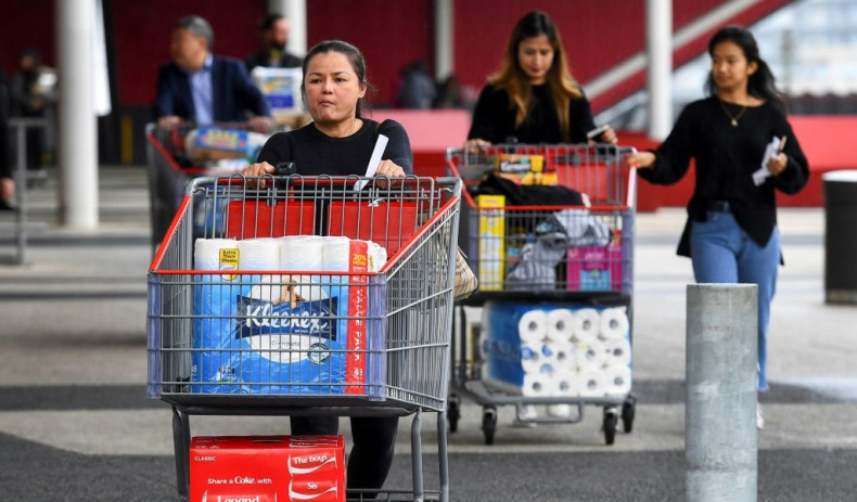People leave a Costco warehouse with rolls of toilet paper amongst their groceries in Melbourne on March 5, 2020
