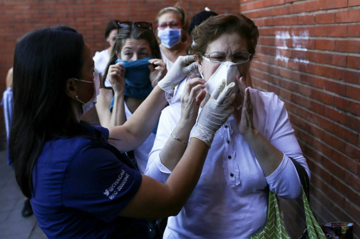 Une femme place un masque devant son visage avant d'entrer sur un marché à Caracas, au Venezuela, le 15 mars 2020