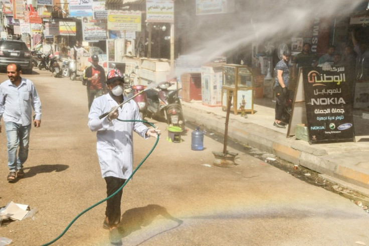 A municipality worker disinfects a street in Iraq's southern city of Nasiriyah as a precaution against the coronavirus outbreak