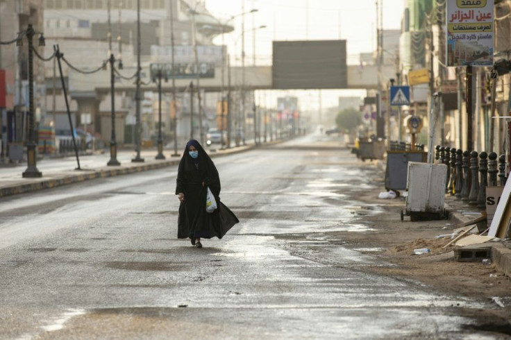 A mask-clad woman walks along an empty street in Iraq's southern city of Basra