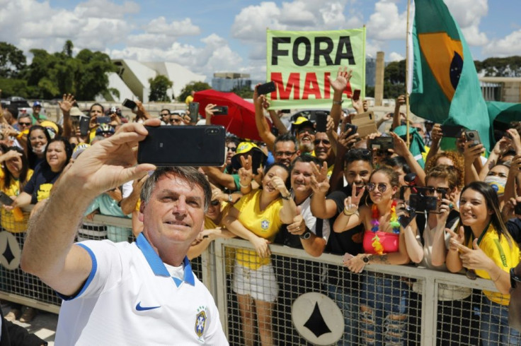 Brazilian President Jair Bolsonaro has come under fire for taking selfies with supporters at a rally, even after his own aides recommended he remain in isolation