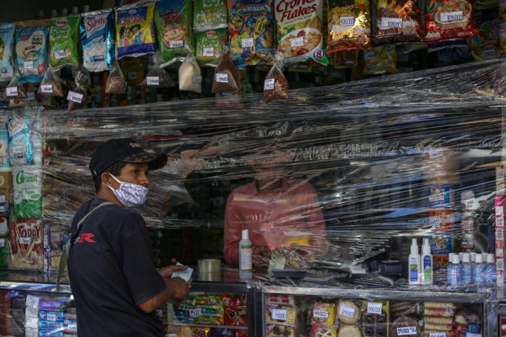 A man shops at a store covered with plastic as a precautionary measure against the spread of the new coronavirus, COVID-19, in Caracas, on March 17, 2020President Nicolas Maduro asked the International Monetary Fund on Tuesday for a $5 billion loan to hel