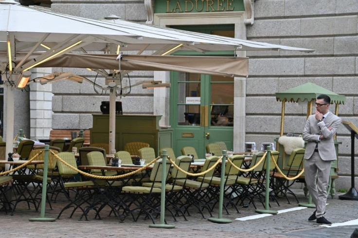 A restaurant employee stands by empty tables in a quiet Covent Garden in central London on March 17, 2020 after the UK government announced stringent social distancing advice