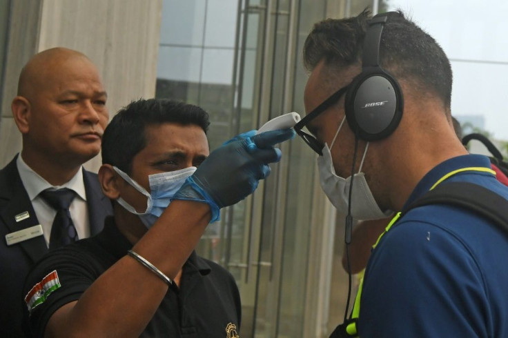 A member of hotel staff wearing a facemask amid concerns over the spread of the COVID-19 novel coronavirus checks the temperature of South African cricket player Faf du Plessis upon his arrival at a hotel in Kolkata