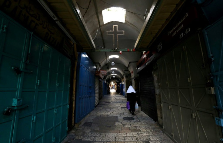 A woman walks past closed shops along a deserted alley in the Old City of Jerusalem