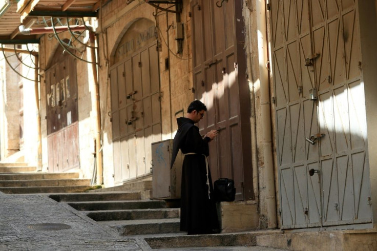 A Fransiscan friar checks his phone in the Old City of Jerusalem on March 16, 2020