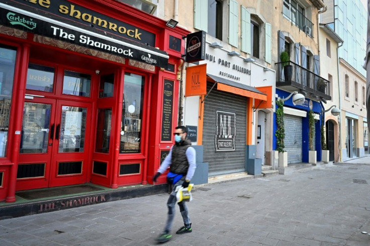 A man wearing a face mask walks past closed bars and restaurants in Marseille, southern France