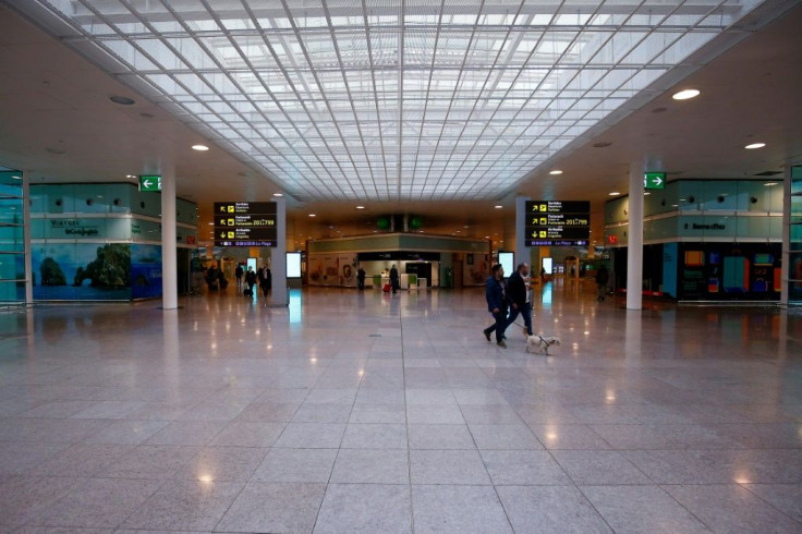 Two people walk a dog at a virtually deserted Terminal 1 of Barcelona's El Prat -- while in Madrid, barking is one of few sounds breaking the silence in the capital's desrted streets