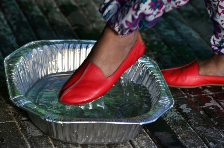 A woman disinfects her shoes before entering a supermarket during a break in the curfew imposed by the government against the spread of the new coronavirus, in the Honduran capital Tegucigalpa, on March 19, 2020