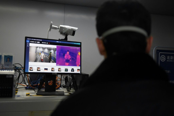 A security guard keeps watch as an AI-powered system screens commuters for fevers while they enter a Beijing metro station