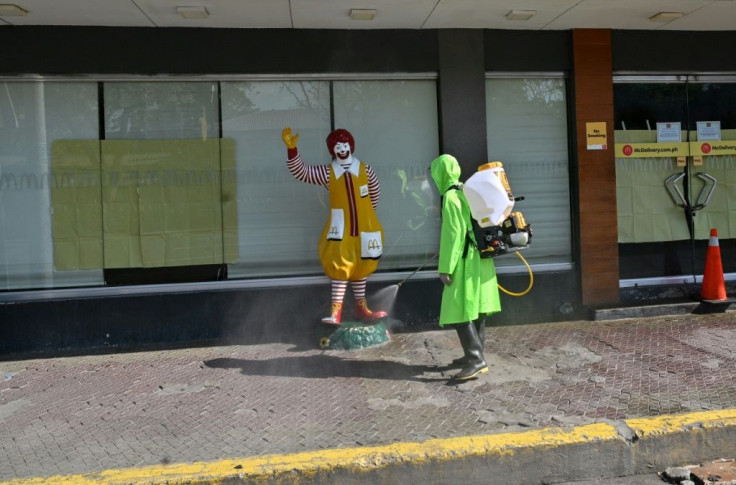 A city worker in a protective suit disinfects a street as a preventive measure against the coronavirus in Manila