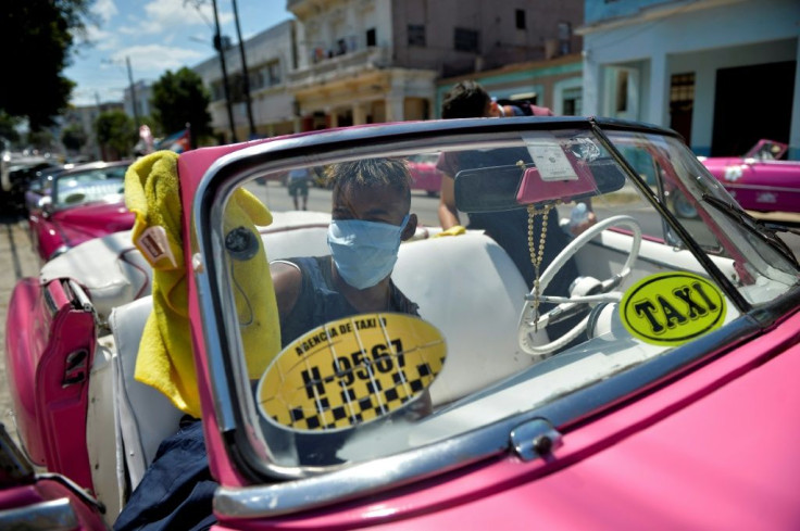 Workers of a private taxi company disinfect old American cars wearing face masks as a preventive measure against the spread of the new coronavirus