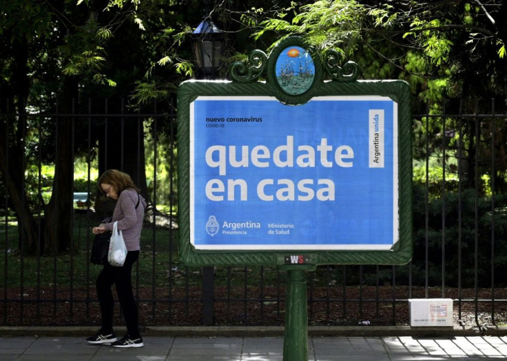 A woman walks near an Argentine health ministry sign in Buenos Aires that reads "Stay at home"