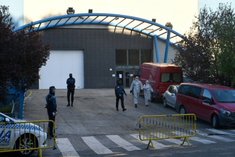 Policemen and undertakers wearing protective suits stand outside the Palacio de Hielo (Ice Palace) in Madrid s
