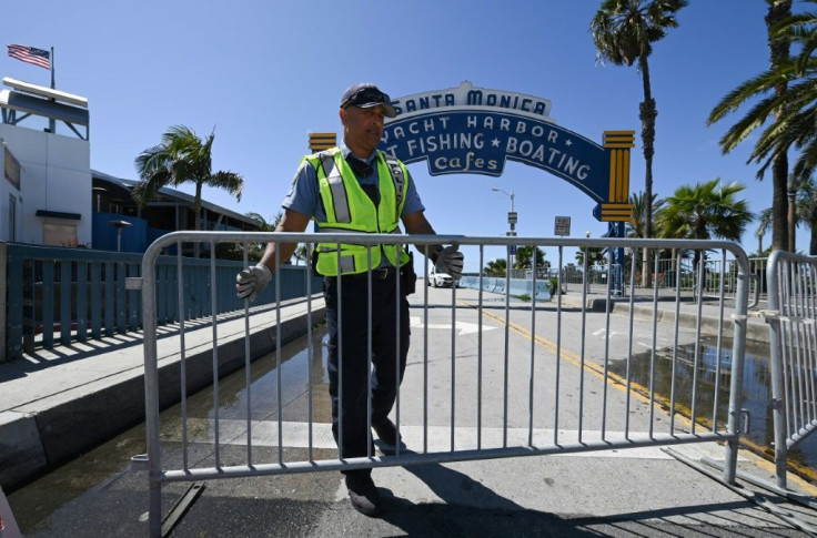 A police officer closes access to the Santa Monica pier in Santa Monica, California as around a third of Americans live under various phases of lockdown