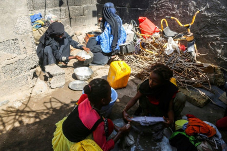 Yemeni women from a poor family prepare food for cooking as other girls wash clothes in a shack in the Red Sea port city of Hodeida in January 2019