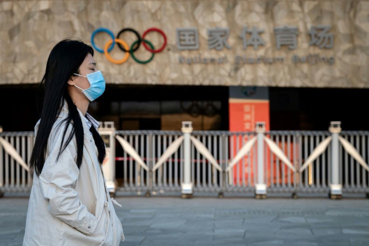 Passers-by at Beijing's Olympic Park wear protective face masks as the coronavirus pandemic causes problems around the world