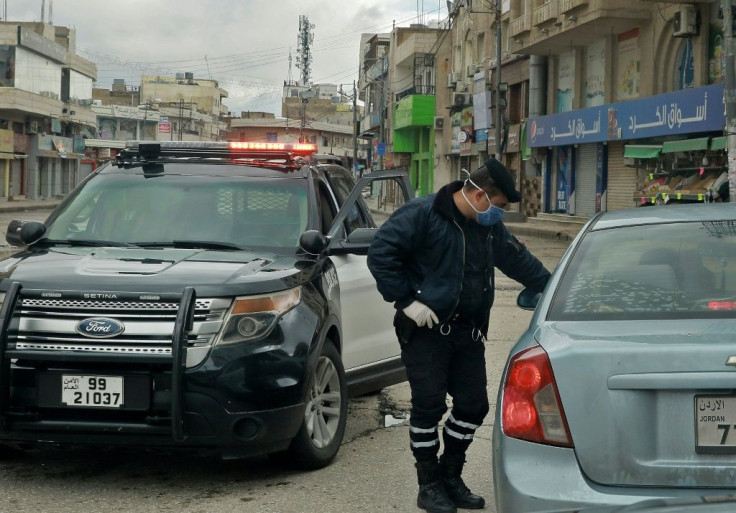 A policeman speaks to a driver at a checkpoint in the Jordanian capital Amman during a nationwide curfew imposed to control the spread of the novel coronavirus
