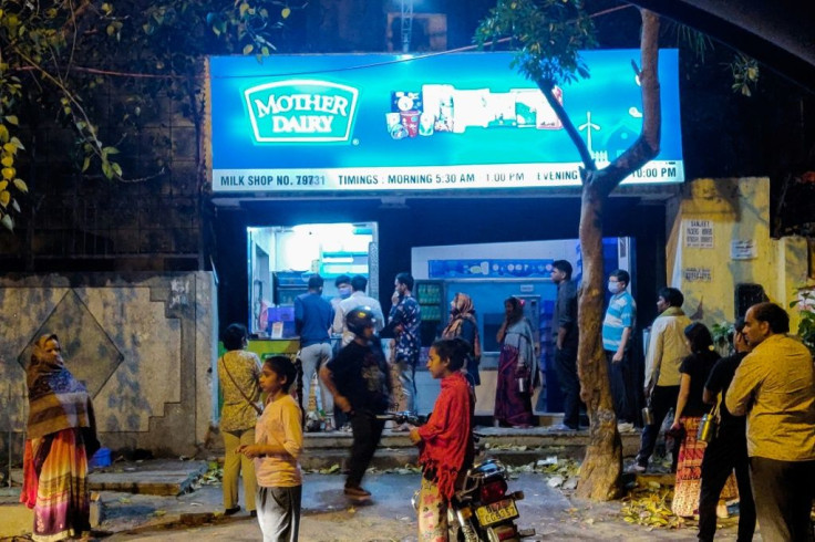 People line up at a dairy shop to buy milk in New Delhi on March 24