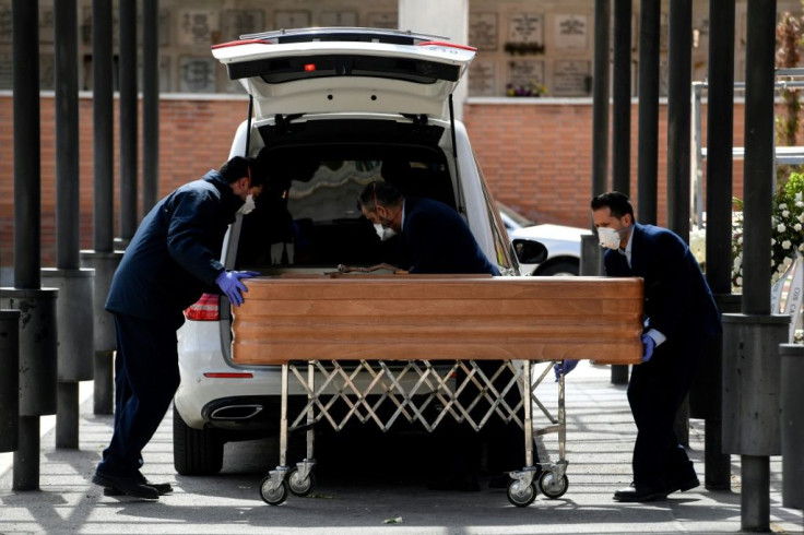 Mortuary employees wearing face masks wheel a coffin into the crematorium of La Almudena cemetery in Madrid during the funeral of a COVID-19 coronavirus victim