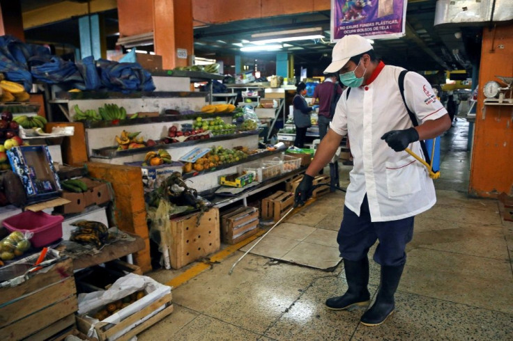 An employee wears a face mask and gloves while disinfecting the Santa Clara market in Quito, on March 21